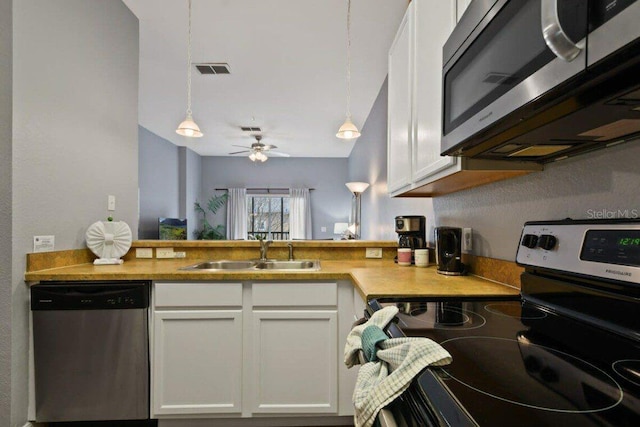 kitchen with decorative light fixtures, white cabinetry, sink, and appliances with stainless steel finishes