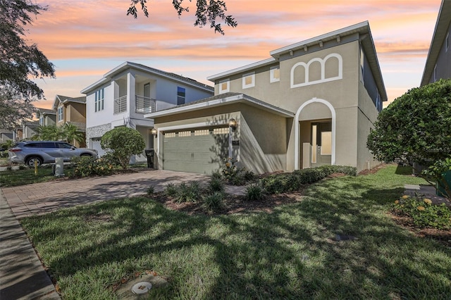 view of front of property featuring a balcony, a garage, and a lawn