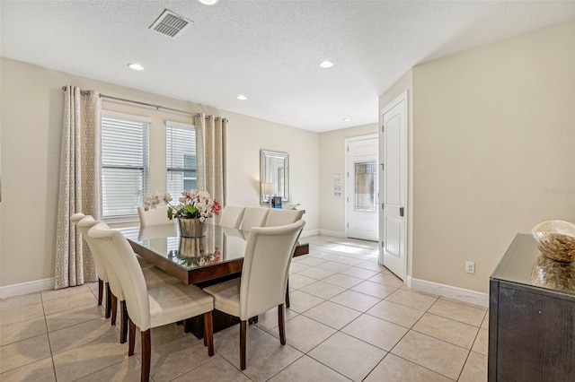 dining space with a textured ceiling and light tile patterned flooring