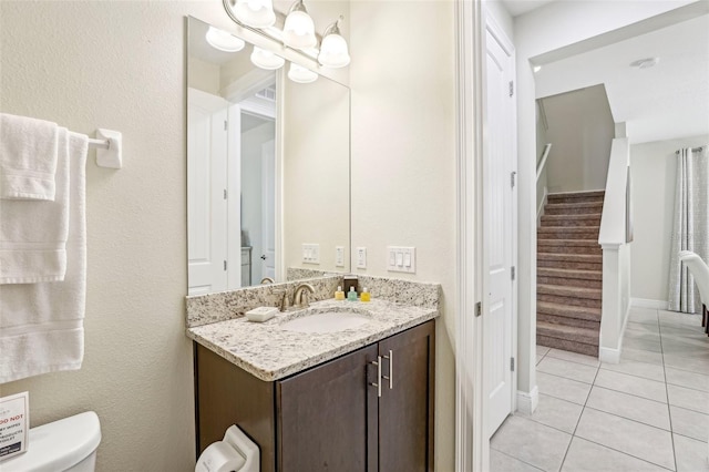 bathroom with tile patterned flooring, vanity, an inviting chandelier, and toilet