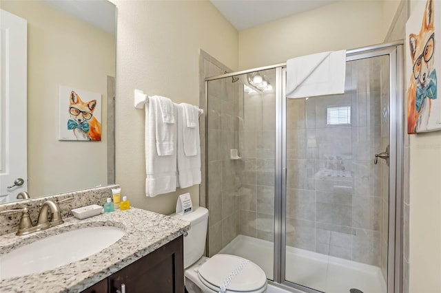 bathroom featuring vanity, toilet, and a shower with door