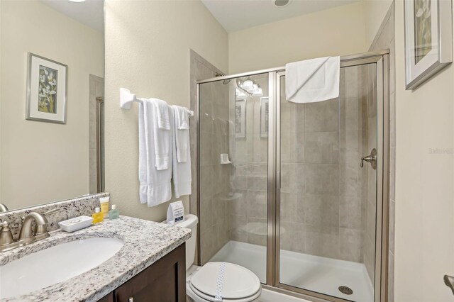 bathroom featuring vanity, toilet, and a shower with door