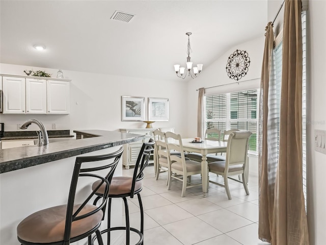 dining room with sink, light tile patterned floors, vaulted ceiling, and a notable chandelier