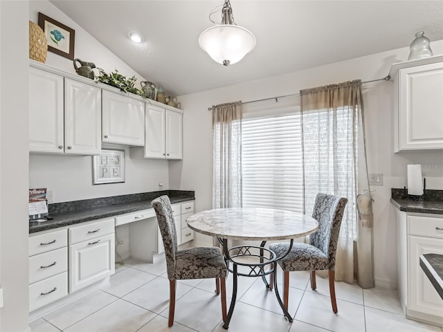 tiled dining space with built in desk and vaulted ceiling