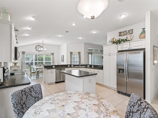 kitchen with a center island, kitchen peninsula, vaulted ceiling, white cabinetry, and stainless steel appliances