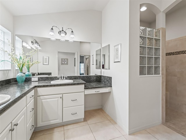 bathroom with tile patterned flooring, a tile shower, and vanity