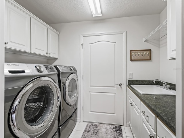 laundry room with light tile patterned flooring, cabinets, sink, and washing machine and clothes dryer