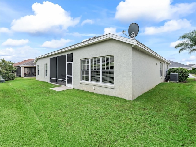 back of property featuring a sunroom, central AC unit, and a yard