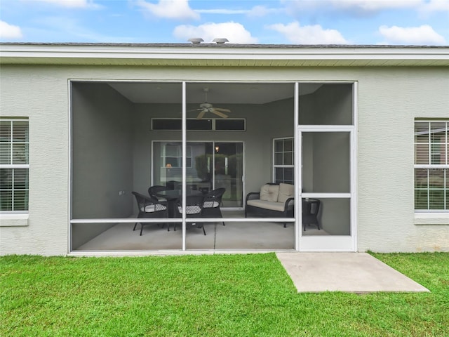 rear view of house with ceiling fan, a lawn, and a sunroom