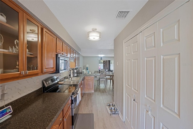 kitchen featuring decorative backsplash, stainless steel appliances, sink, dark stone countertops, and light hardwood / wood-style floors