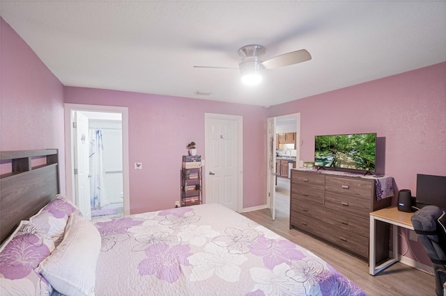 bedroom featuring ensuite bath, light hardwood / wood-style flooring, and ceiling fan