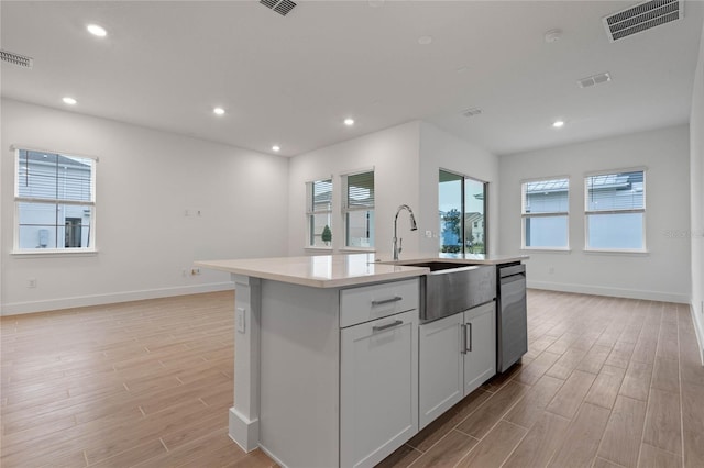 kitchen featuring sink, dishwasher, white cabinets, and a kitchen island with sink