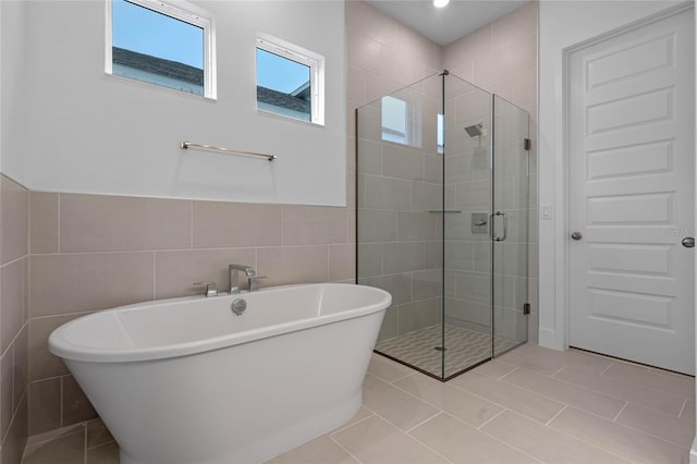 bathroom with tile walls and shower with separate bathtub