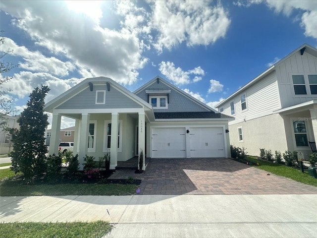 view of front of house with a porch, decorative driveway, and an attached garage