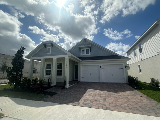 view of front of home with covered porch, an attached garage, and decorative driveway