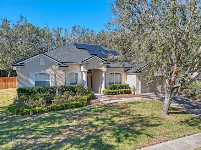 ranch-style house with a garage, solar panels, and a front yard