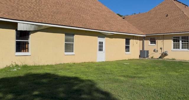 rear view of property featuring central AC and a yard