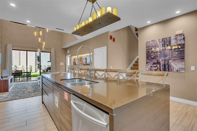 kitchen featuring dishwasher, pendant lighting, sink, and an island with sink