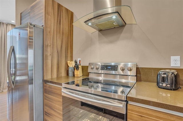 kitchen with island exhaust hood, appliances with stainless steel finishes, and hardwood / wood-style flooring