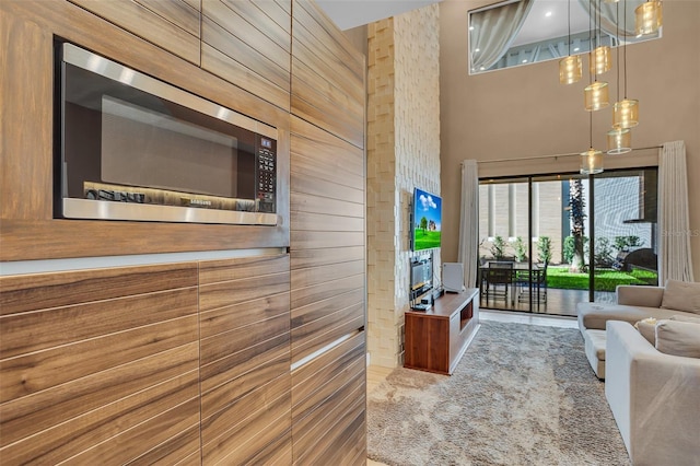 living room featuring carpet, a high ceiling, and wood walls