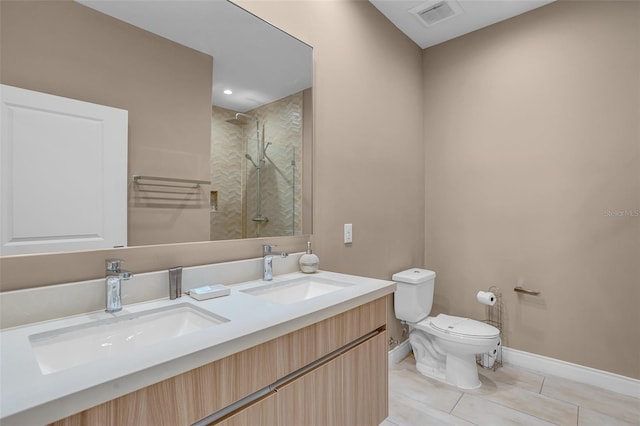 bathroom featuring tile patterned flooring, vanity, toilet, and a tile shower