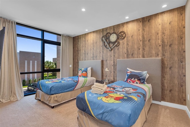 bedroom with carpet flooring, floor to ceiling windows, and wood walls