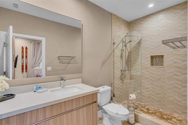 bathroom with vanity, toilet, and a tile shower