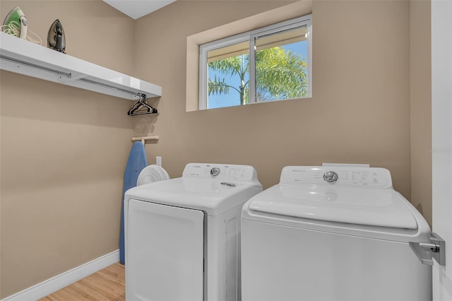 clothes washing area with independent washer and dryer and light hardwood / wood-style flooring