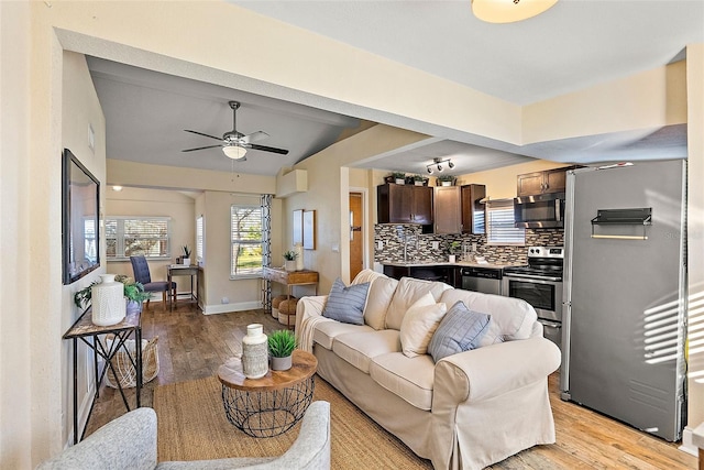 living room featuring vaulted ceiling, light hardwood / wood-style flooring, and ceiling fan