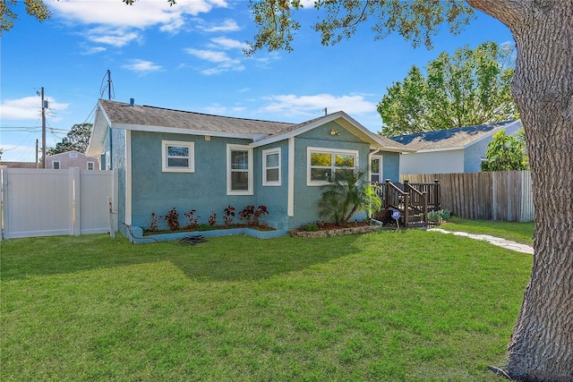 back of property with stucco siding, fence, and a lawn