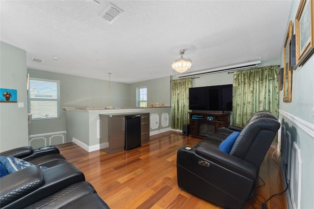 living room featuring an inviting chandelier, a textured ceiling, and hardwood / wood-style flooring