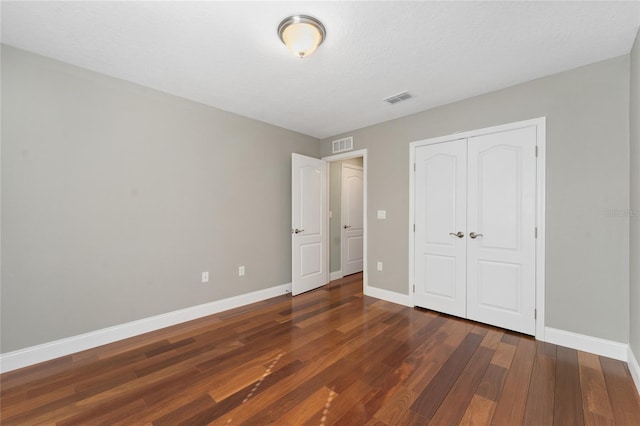 unfurnished bedroom with a closet, dark wood-type flooring, and a textured ceiling