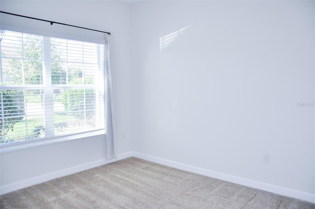 spare room featuring plenty of natural light and light colored carpet