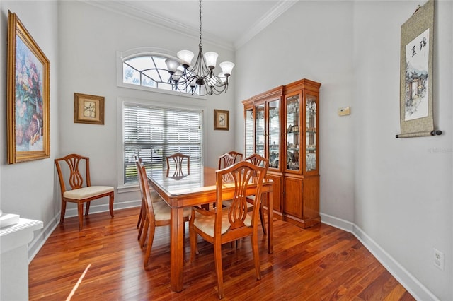 dining area with crown molding, a high ceiling, a notable chandelier, and hardwood / wood-style flooring