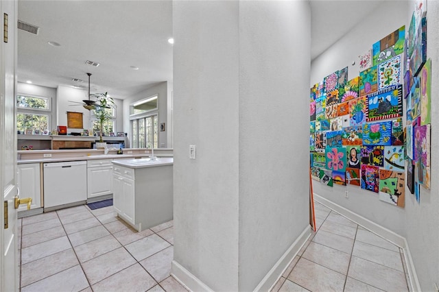 kitchen with white dishwasher, white cabinets, ceiling fan, light tile patterned floors, and a kitchen island