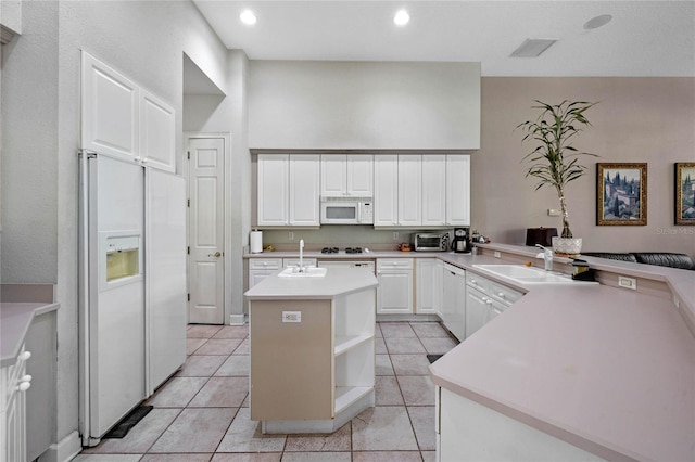 kitchen with sink, kitchen peninsula, white appliances, a kitchen island with sink, and white cabinets