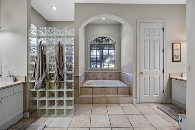 bathroom with tile patterned flooring, vanity, and tiled bath