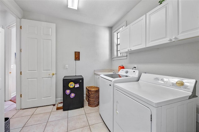 clothes washing area featuring light tile patterned floors, cabinets, a textured ceiling, and independent washer and dryer