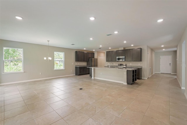 kitchen featuring sink, light tile patterned floors, appliances with stainless steel finishes, dark brown cabinets, and a chandelier