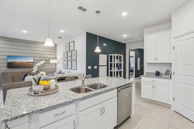 kitchen with white cabinets, sink, hanging light fixtures, stainless steel dishwasher, and an island with sink