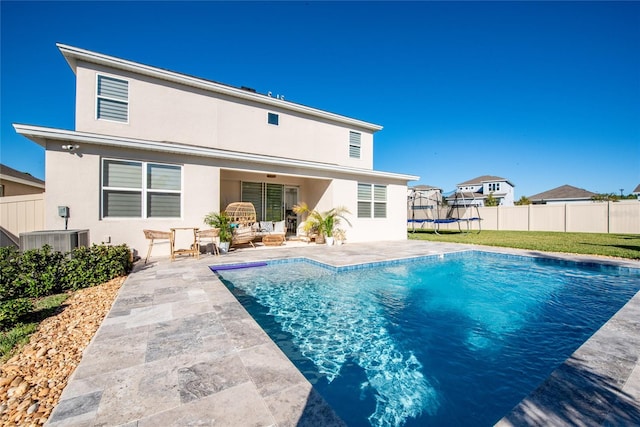 back of house with a patio, a trampoline, a fenced in pool, and central air condition unit