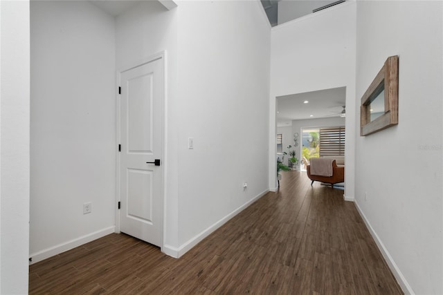 hall with a high ceiling and dark hardwood / wood-style floors