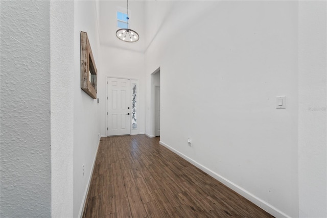 hallway with dark wood-type flooring and a notable chandelier