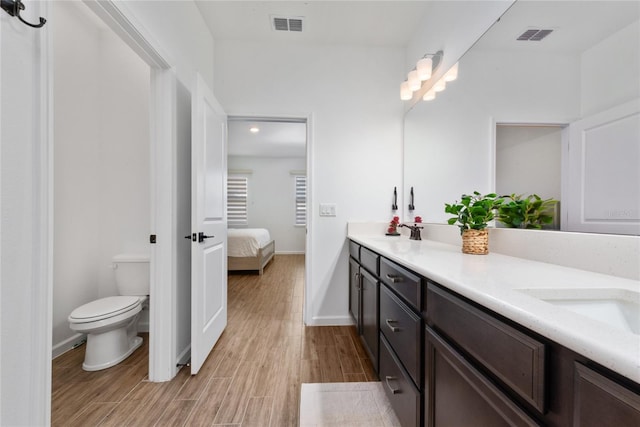 bathroom featuring wood-type flooring, vanity, and toilet