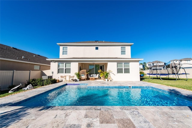 rear view of house featuring a trampoline, a fenced in pool, and a patio area