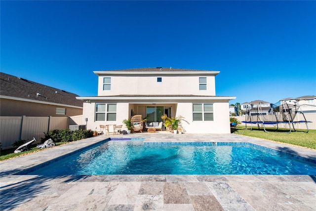 4381 Davos Dr, Clermont, FL 34711 - back of property featuring a trampoline, a patio, and stucco siding