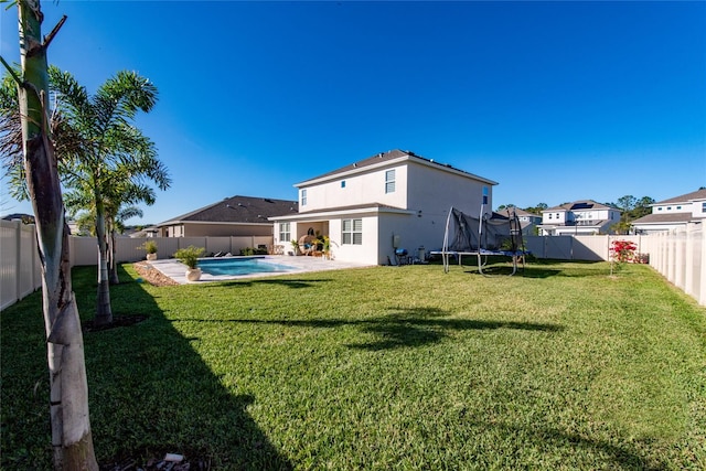 rear view of property with a trampoline, a patio area, a fenced in pool, and a lawn