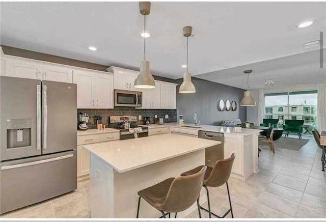 kitchen featuring white cabinets, sink, hanging light fixtures, decorative backsplash, and stainless steel appliances