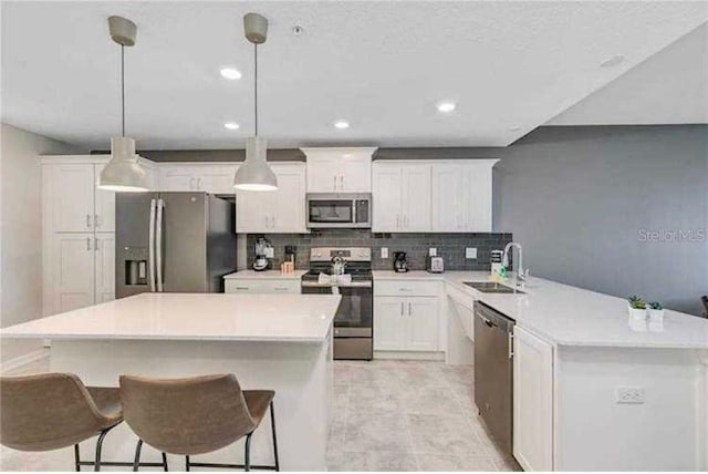 kitchen with white cabinets, sink, hanging light fixtures, decorative backsplash, and stainless steel appliances