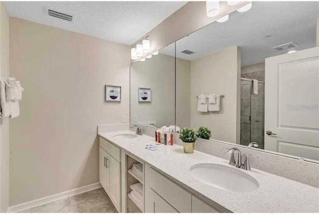 bathroom with tile patterned floors, vanity, a textured ceiling, and walk in shower